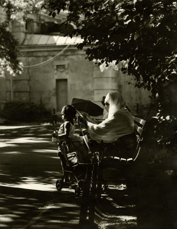 Image of a mother braiding her daughter's hair in a park.
