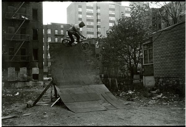 Image of a boy riding a bicycle up on a quarter pipe.