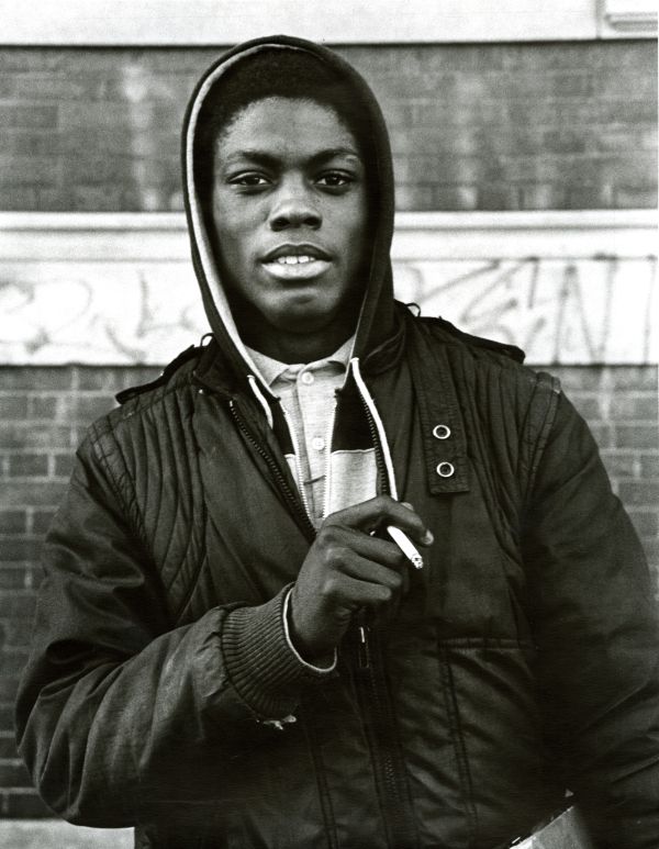 Image of high school student holding a cigarette while facing  the camera.