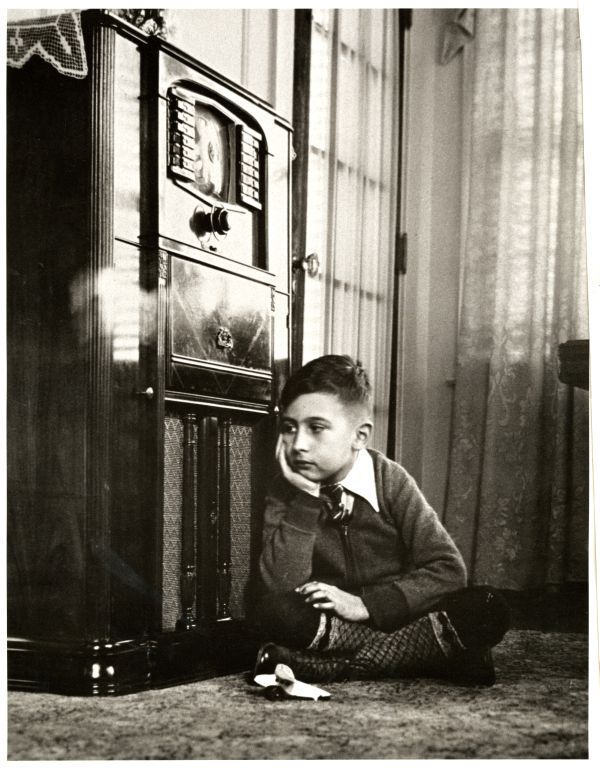 Image of a boy lying down while listening to a 1940s style radio