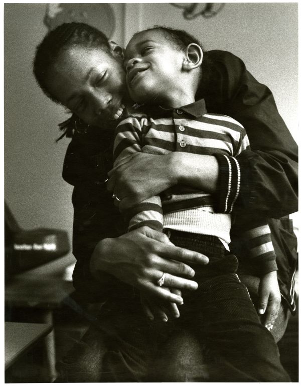 Image of a mother holding her son as both smile.