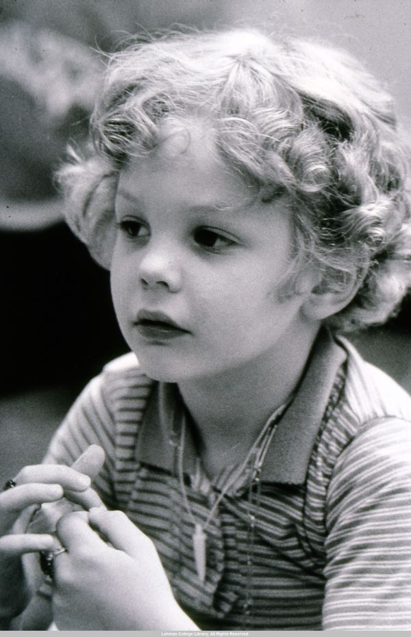 Image of pre school boy with light and curly hair looks off past the camera.