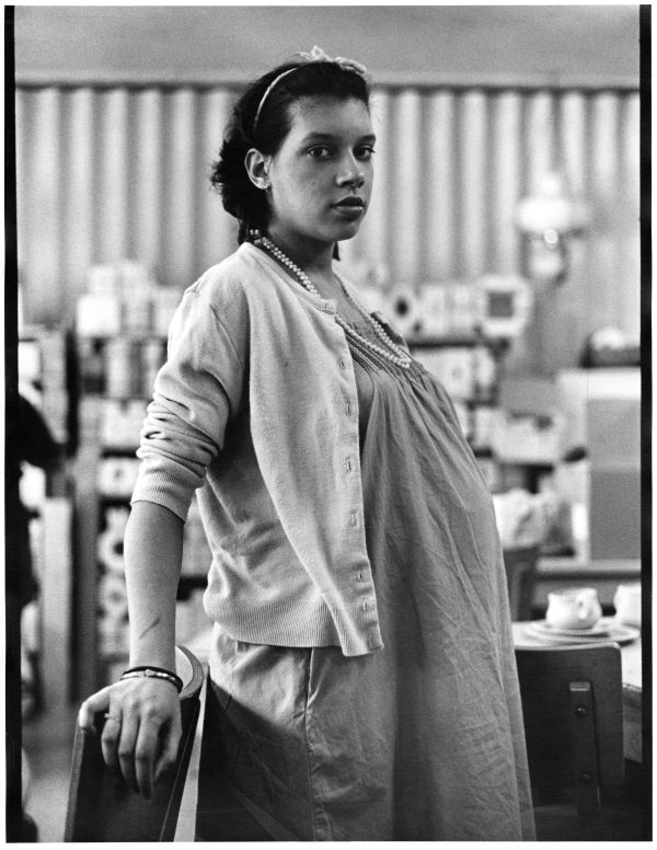 Image of visibly pregnant teenager in hospital facing sideways and looking at camera.