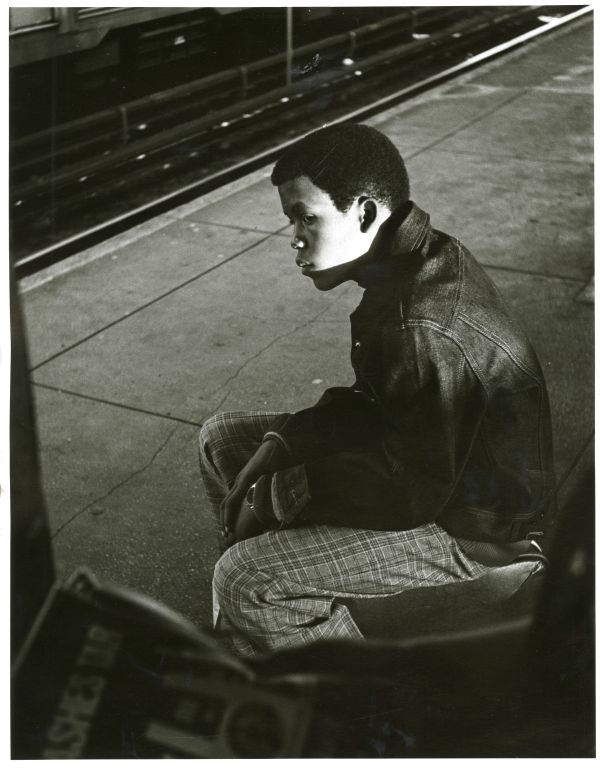 Image of a boy facing left and looking out over a subway platform