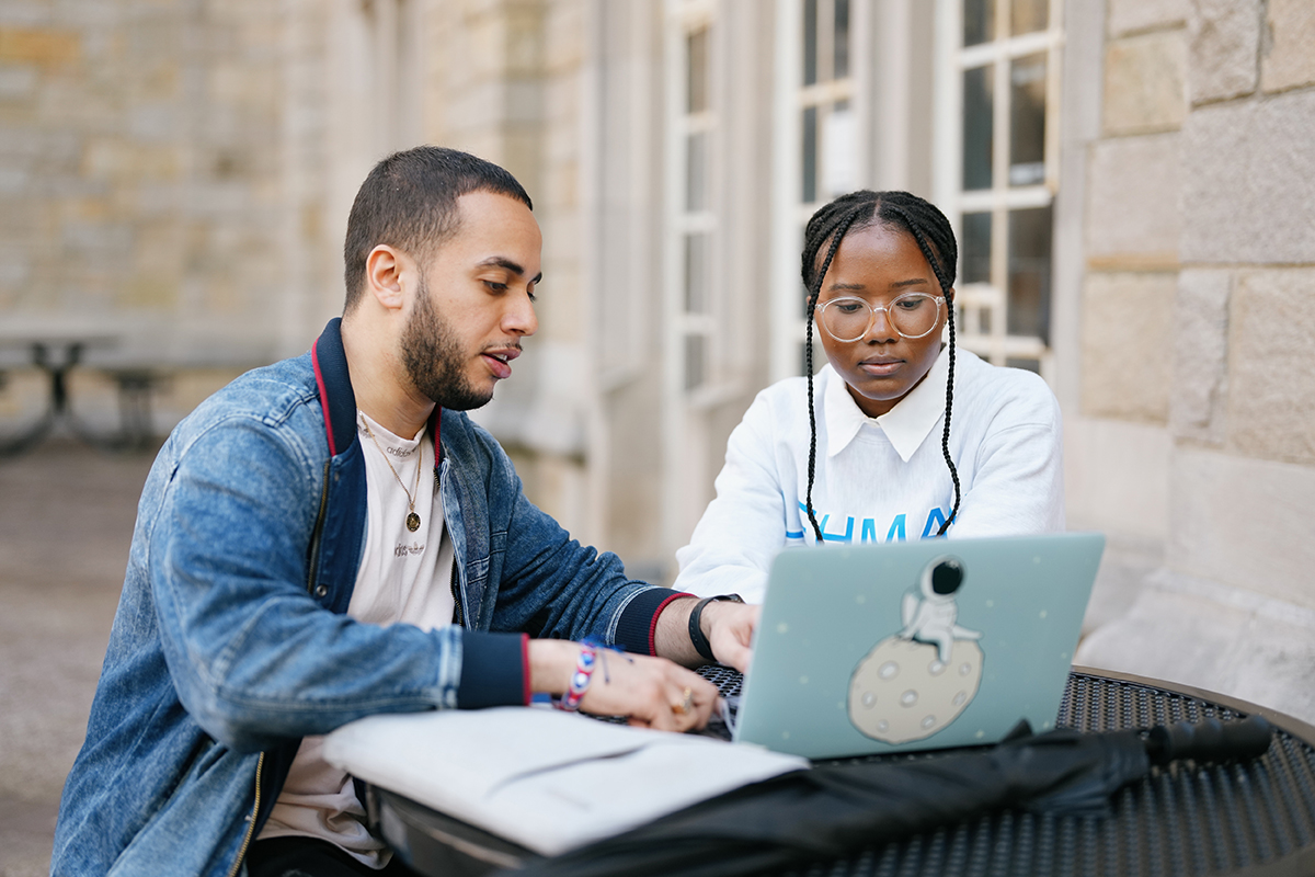Photo of two students studying, looking at laptop