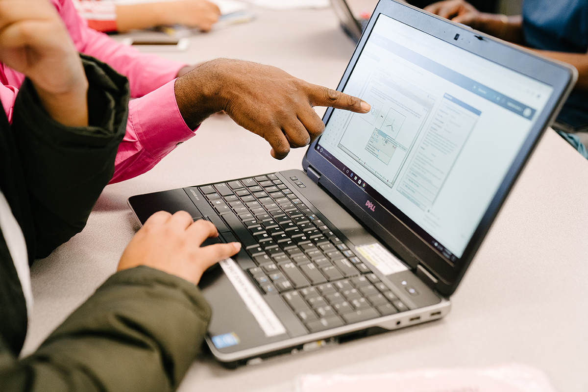 Photo of hands pointing to graphics in a laptop