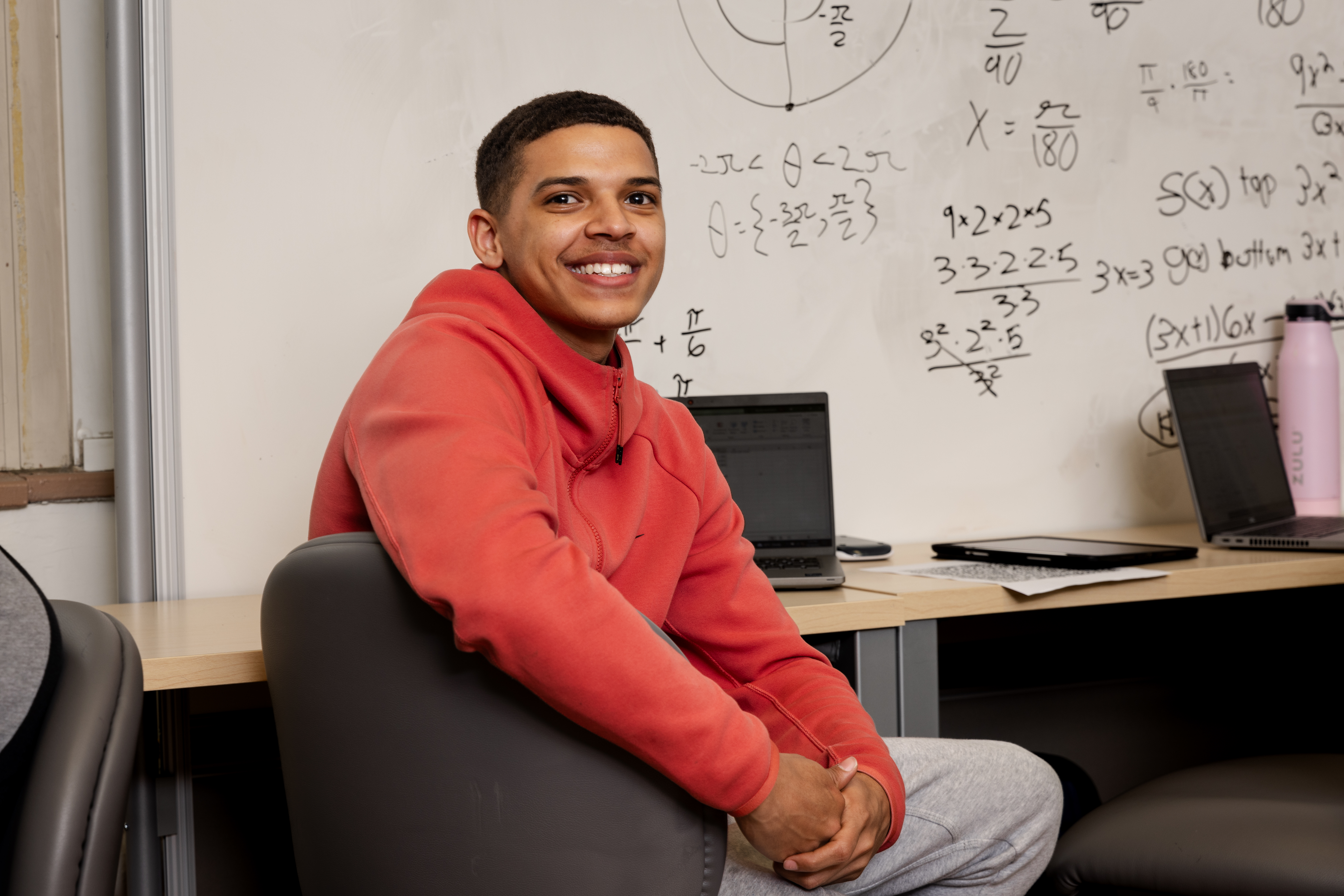 Student sitting in front of a whiteboard with math