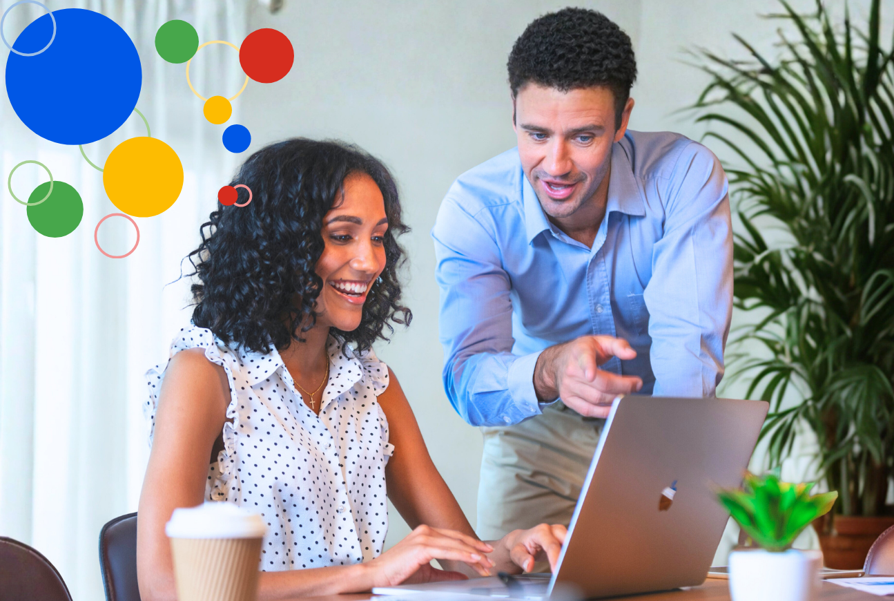 woman sitting in front of the computer and man pointing at it