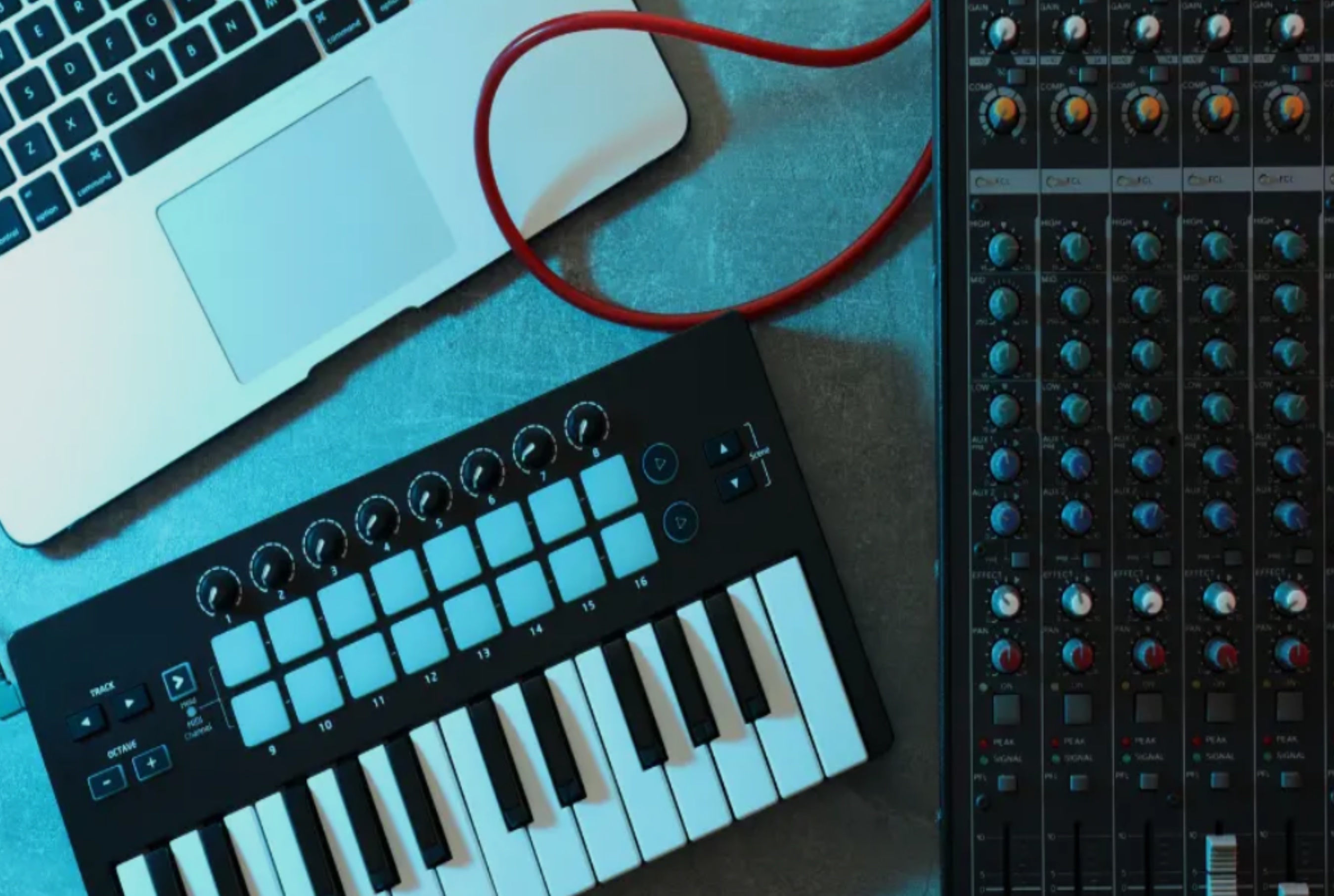An image of a laptop, black and white midi keyboard, and mixer
