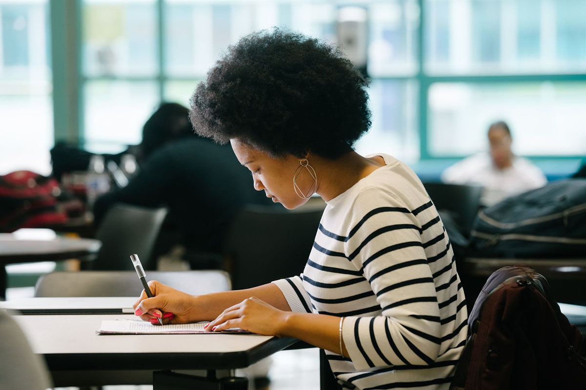 Student filling out paper application for lehman college graduate school program