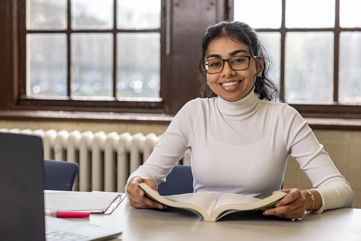 Photo of student smiling with book in hands