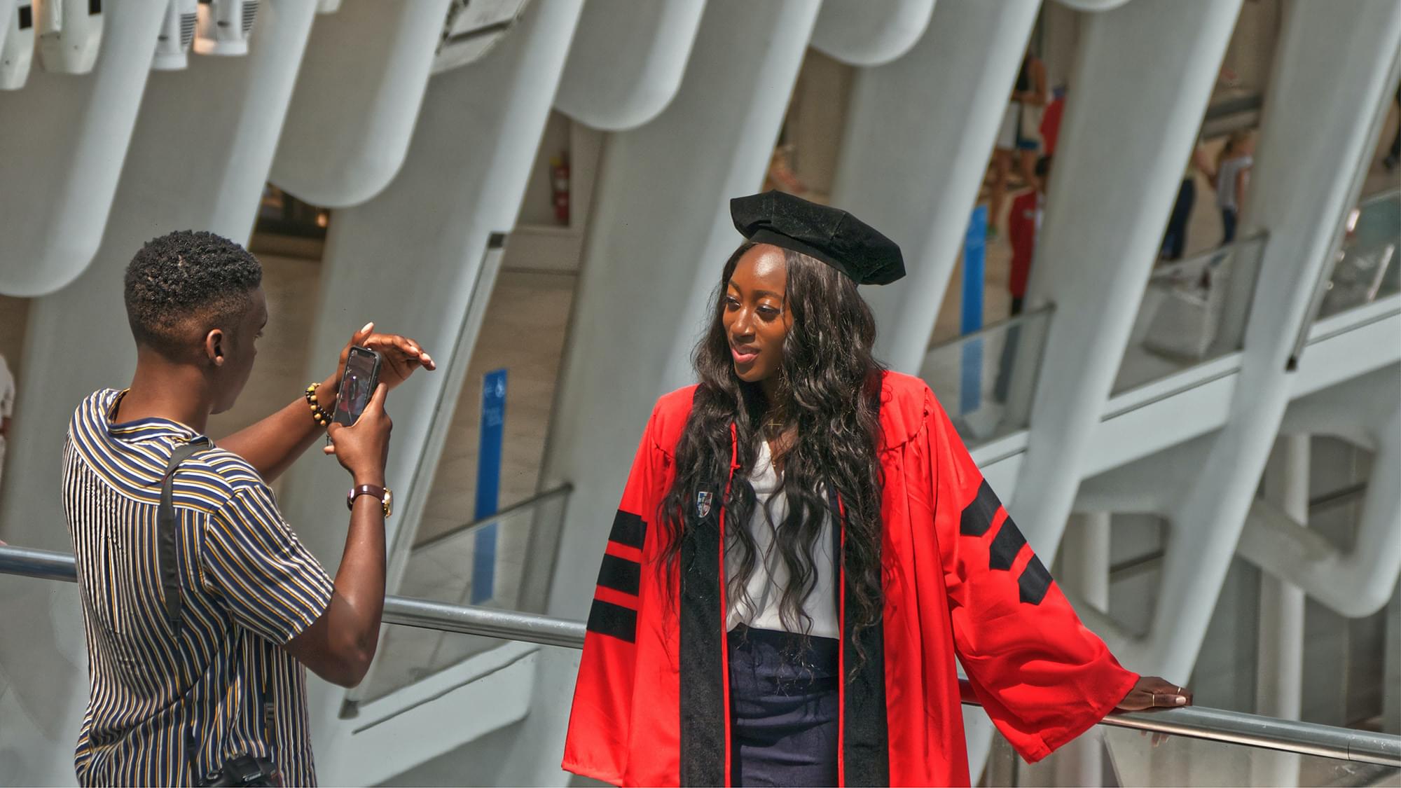 Person taking a photo of a graduate at a graduation ceremony