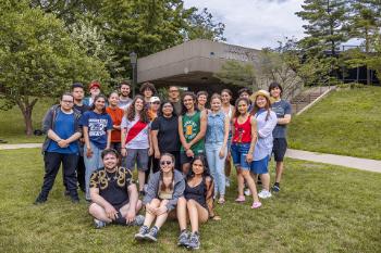 A large group of students poses for the camera on the Lehman College campus quad.