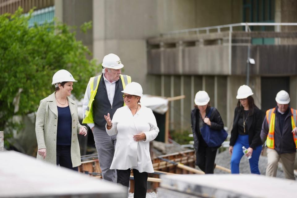a group of people wearing white hard hats exiting a construction site.
