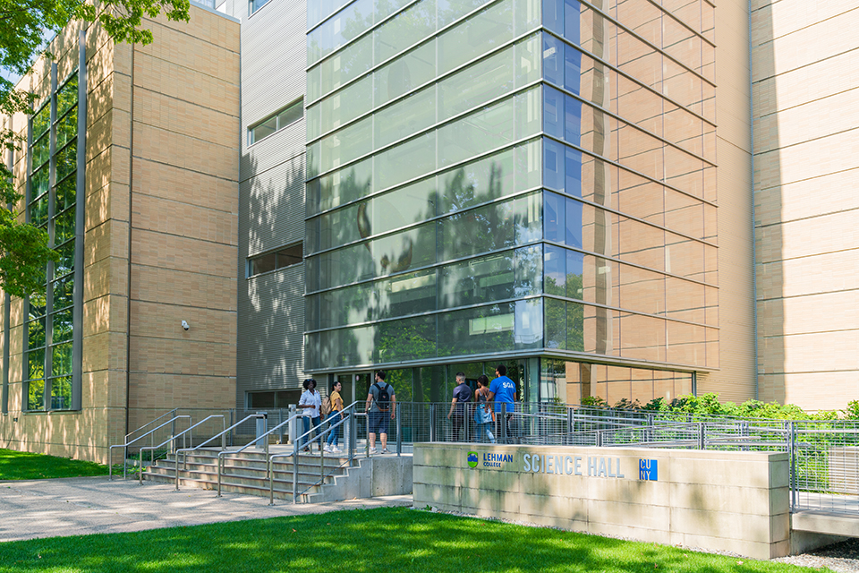 Longshot of a small group of students walking into the lobby of a modern building with a glass front