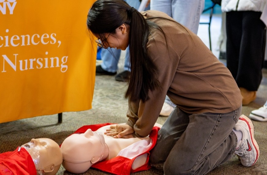 A student practicing CPR on a manikin